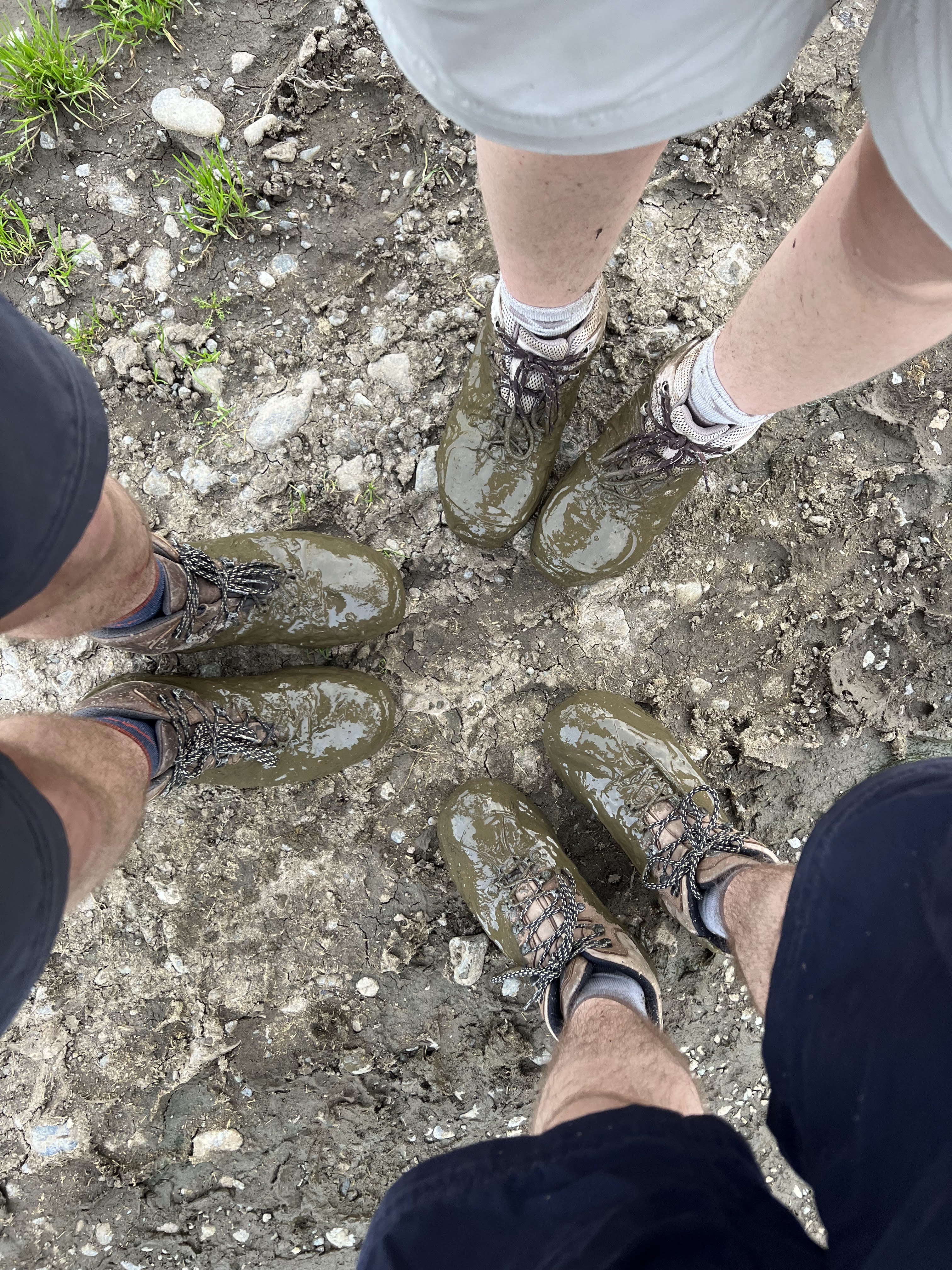 Nick, Mya, and Ben's shoes in a triangle. All are green and covered in slurry